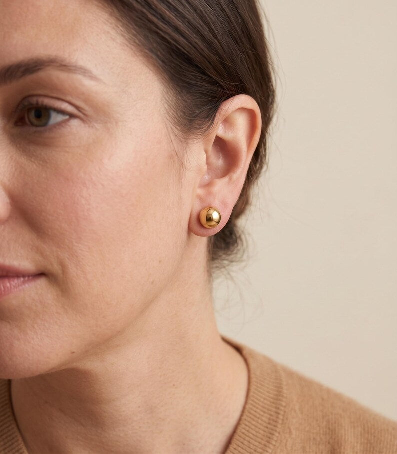 Model wearing gold ball stud earrings