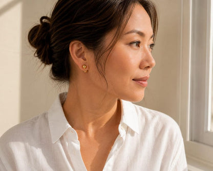 Pair of gold ball stud earrings on display