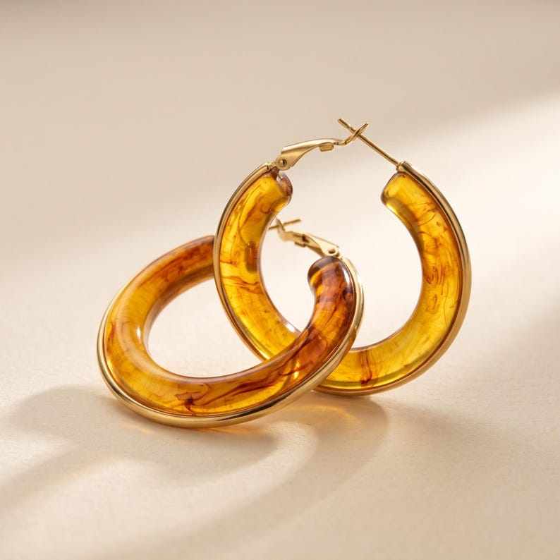Pair of amber resin hoop earrings leaning against each other