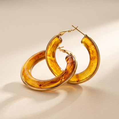 Pair of amber resin hoop earrings leaning against each other