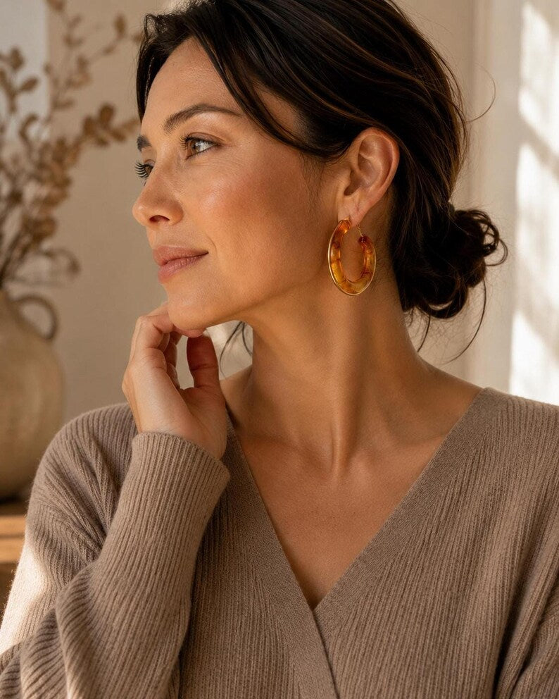 Woman wearing tortoiseshell resin hoop earrings with gold trim