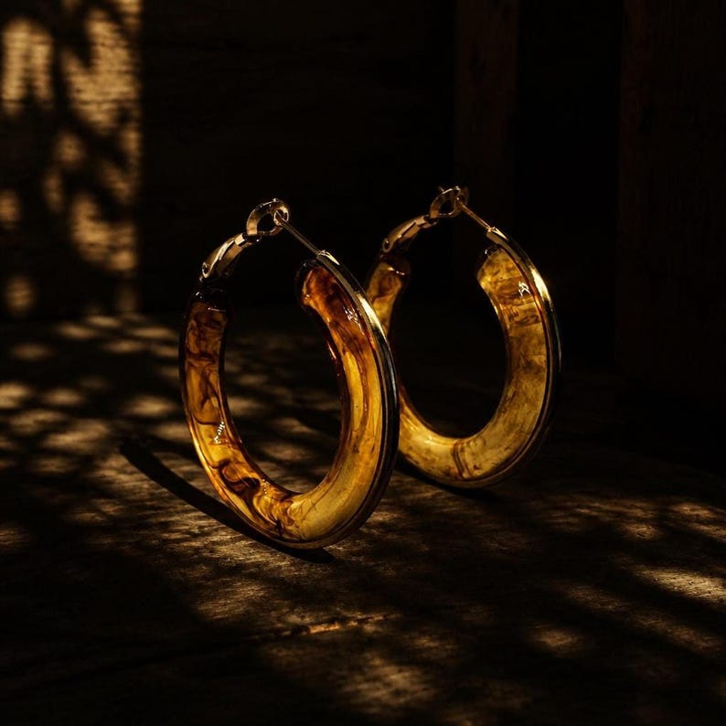 Earrings on dark wooden surface with dappled lighting