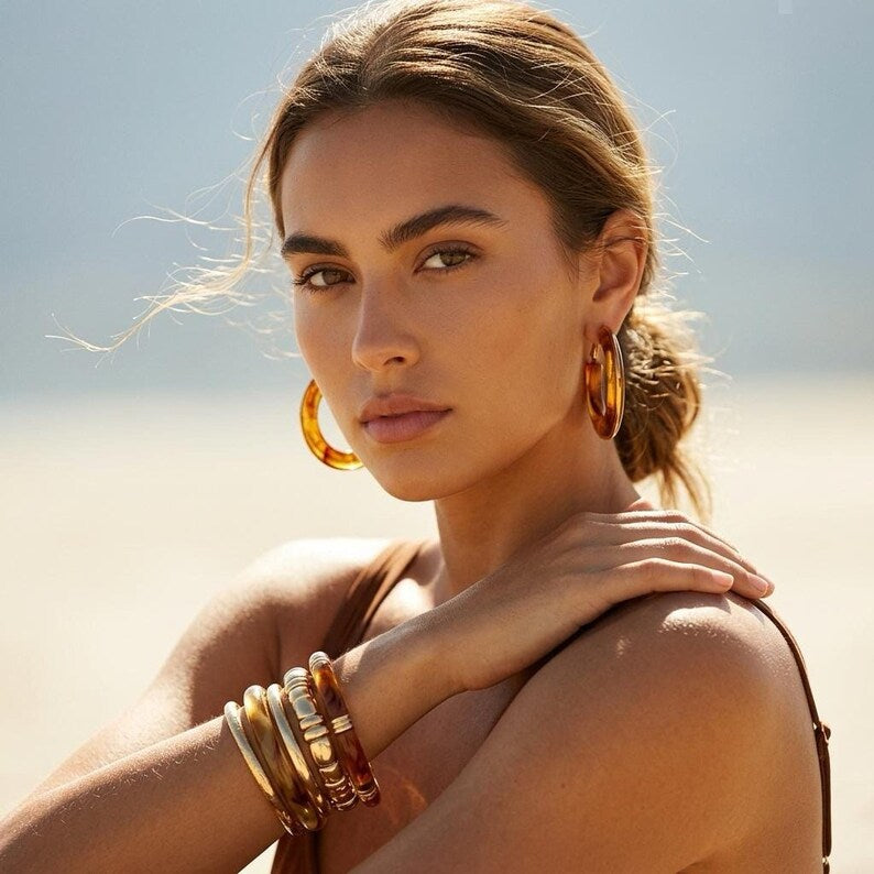 Woman wearing resin hoop earrings and matching bracelets