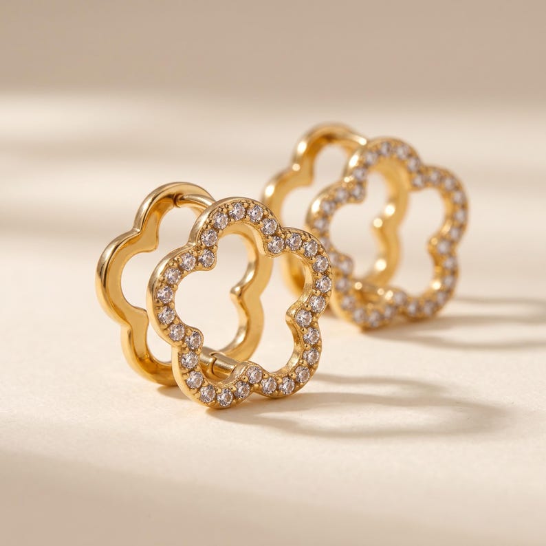 Pair of gold floral huggie earrings displayed at an angle