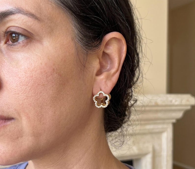 Close-up of gold flower huggie earring worn on earlobe