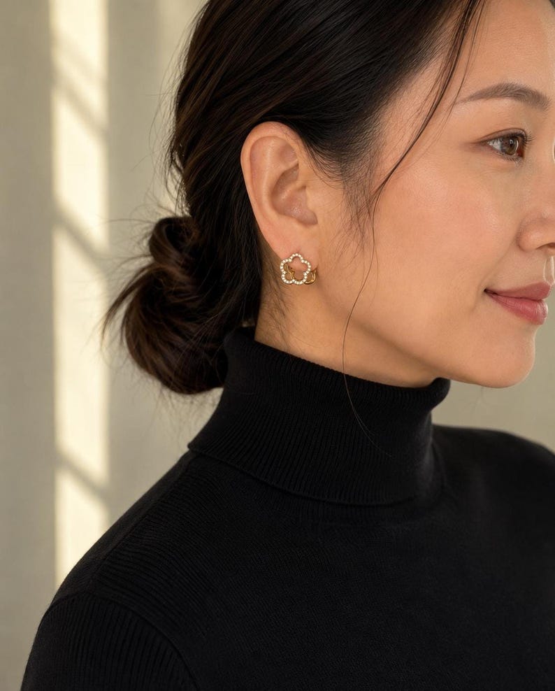 Profile view of gold flower-shaped huggie hoop earring