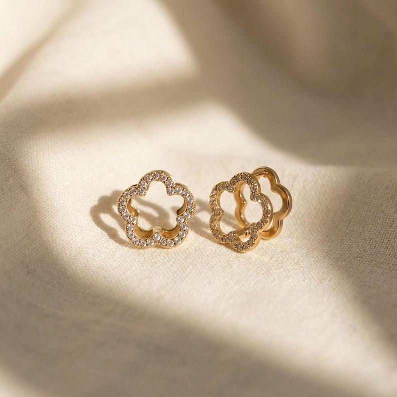 Gold flower huggie earrings on textured cream fabric