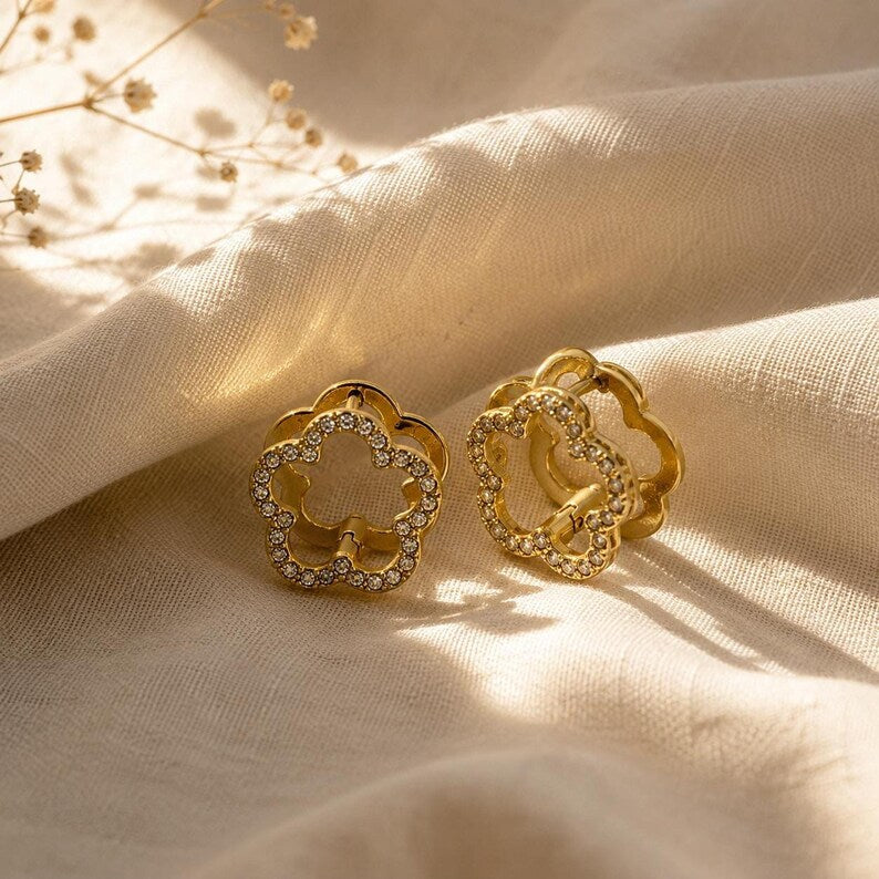 Gold flower pave earrings on draped fabric with dried florals
