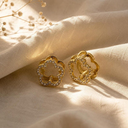 Gold flower pave earrings on draped fabric with dried florals