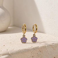 Lilac enamel flower huggie hoop earrings on beige surface