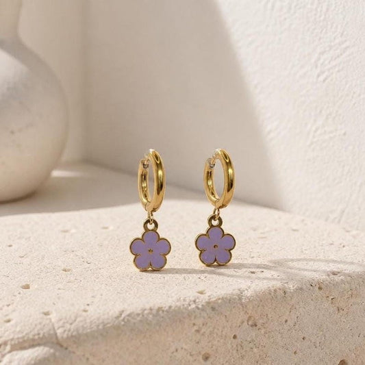 Lilac enamel flower huggie hoop earrings on beige surface