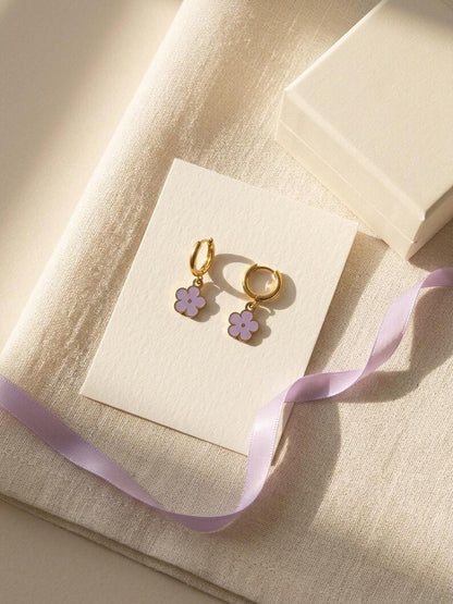 Gold flower huggie earrings displayed with gift box and lilac ribbon