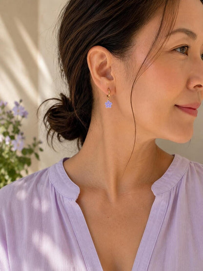 Person wearing gold flower charm huggie earring and lavender top