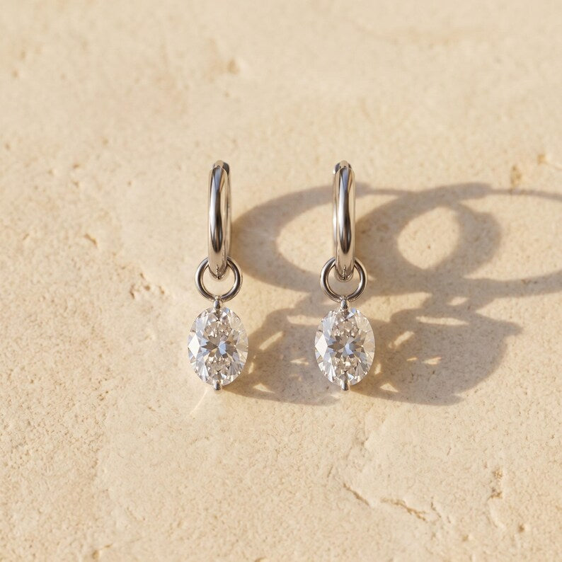 Moissanite huggie earrings lying flat on textured surface