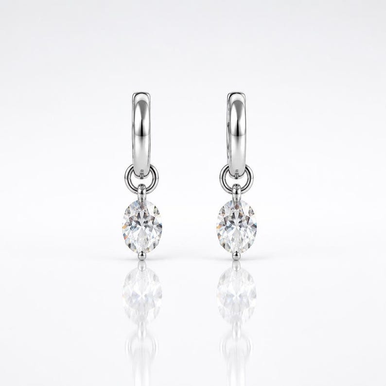 Pair of moissanite huggie hoop earrings on white background