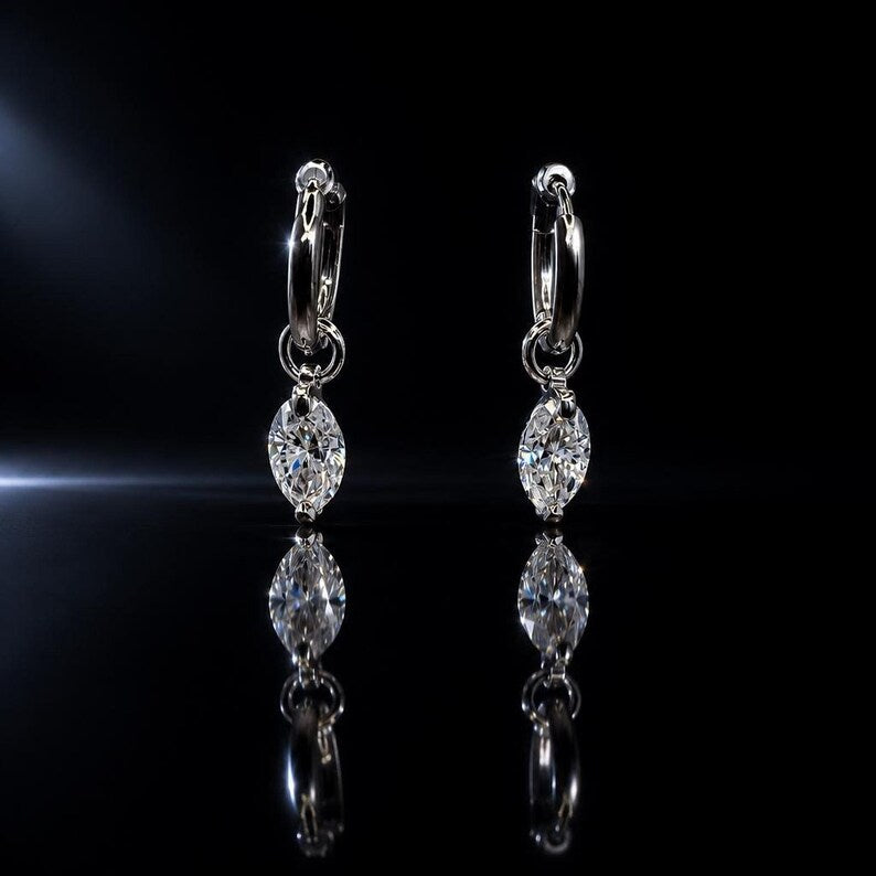 Moissanite huggie earrings reflected on glossy surface