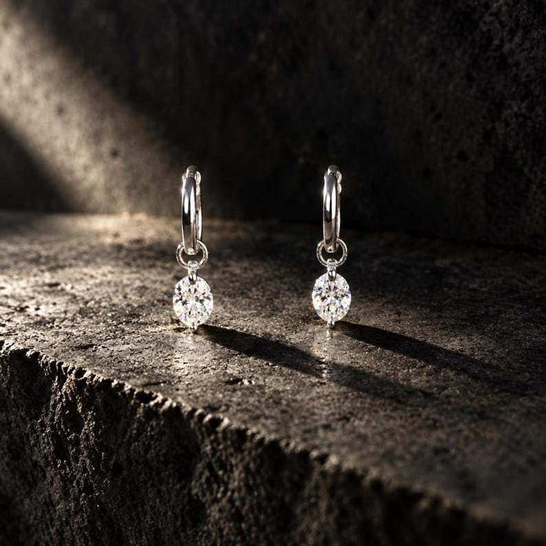 Moissanite huggie earrings on dark stone surface