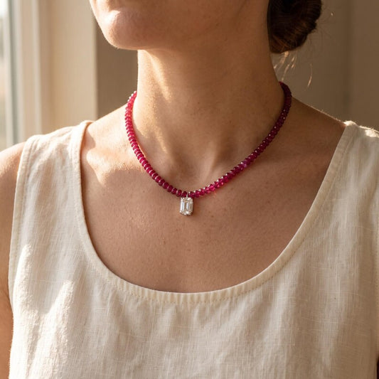 Person wearing ruby beaded choker necklace with moissanite pendant