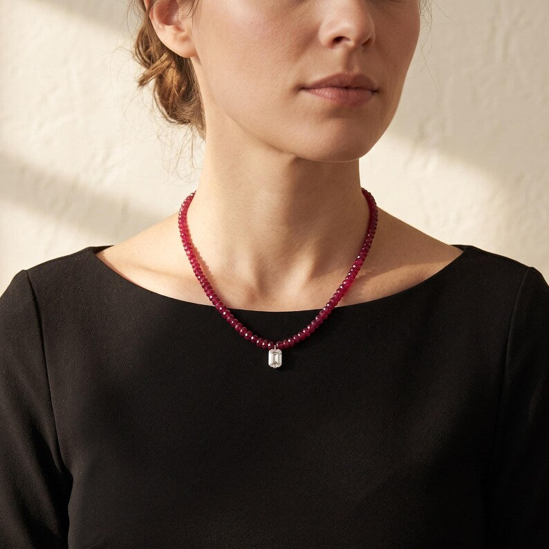 Portrait wearing faceted red bead necklace with rectangular pendant