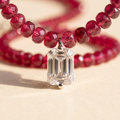Macro shot of emerald-cut moissanite pendant with ruby beads