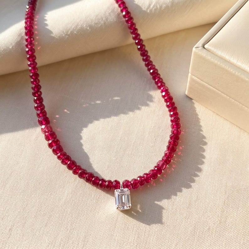 Ruby bead necklace with emerald cut pendant beside jewelry box
