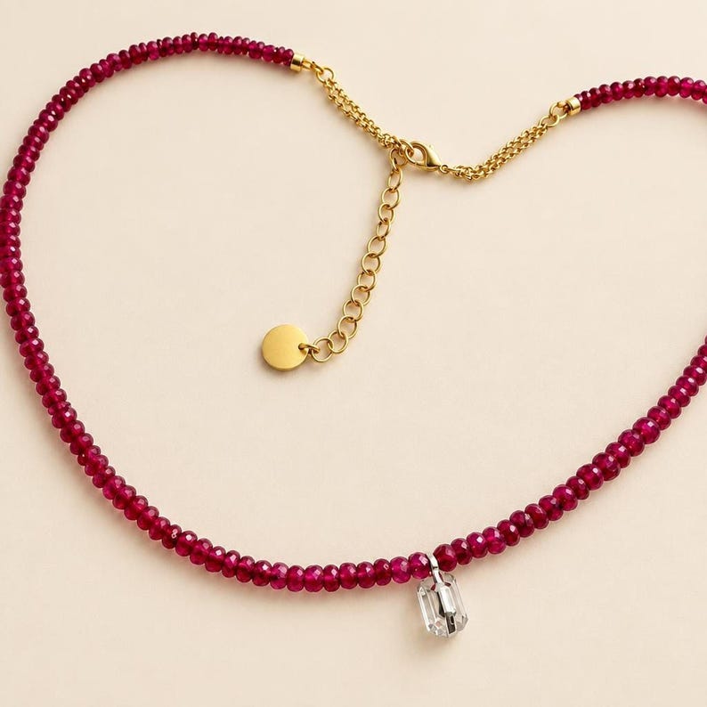 Ruby bead necklace with gold clasp resting flat