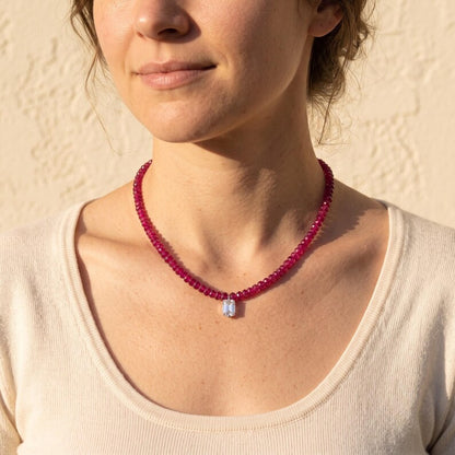 Model wearing ruby bead necklace with emerald-cut stone pendant