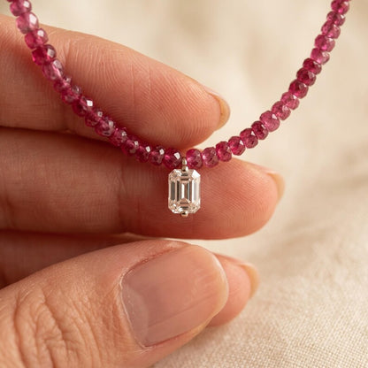 Hand holding center of ruby beaded necklace