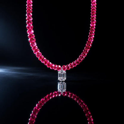 Ruby necklace suspended against dark reflective background