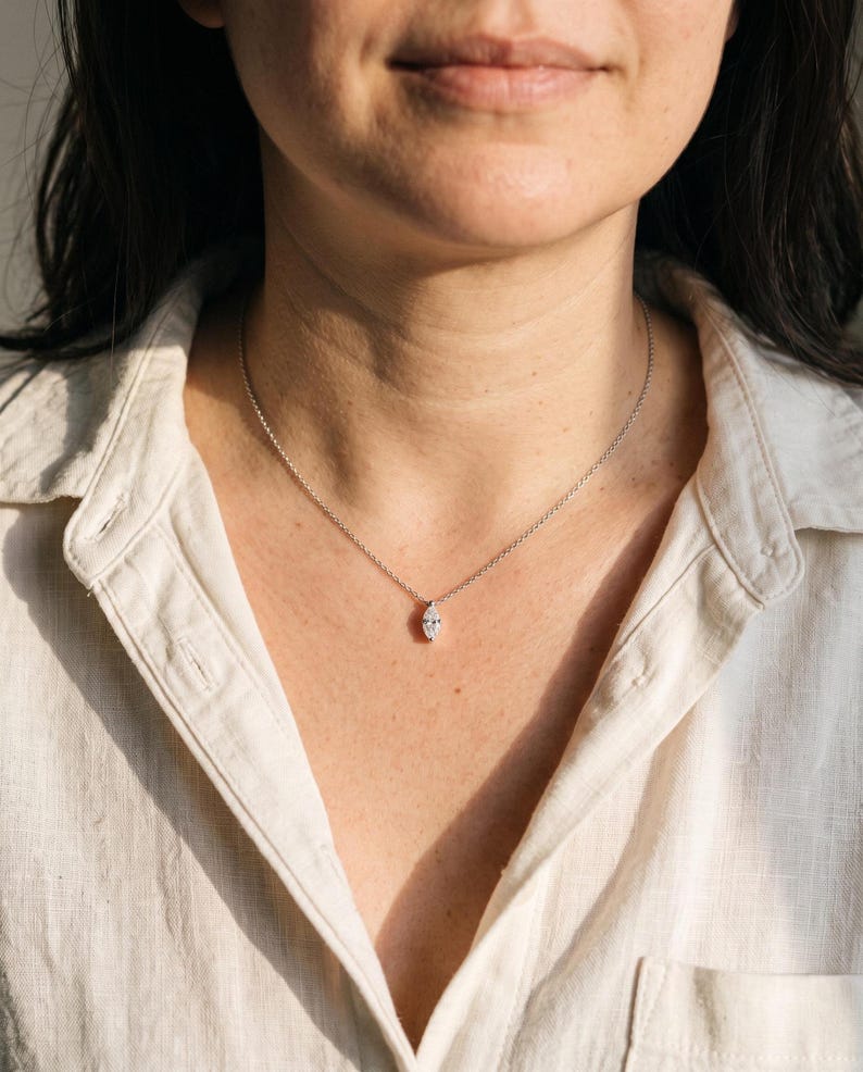Person wearing marquise moissanite necklace with white button-down shirt