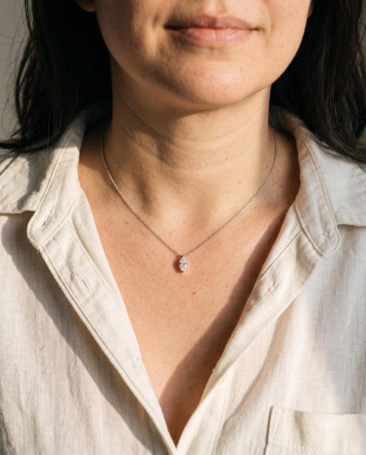 Person wearing marquise moissanite necklace with white button-down shirt