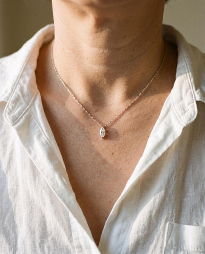Close-up of marquise pendant necklace over unbuttoned white shirt